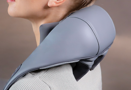 Person using a gray neck and shoulder massager against a neutral background